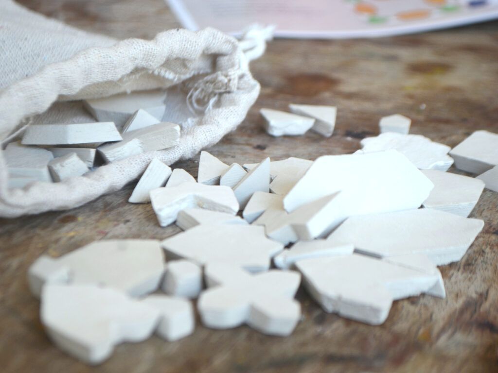 Unbemalte Tonfliesen, die aus einem Baumwollbeutel fallen