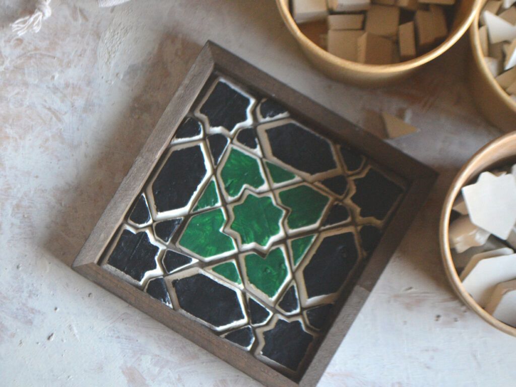 Ein grün-schwarzer geometrischer Untersetzer in einem dunklen Holzrahmen