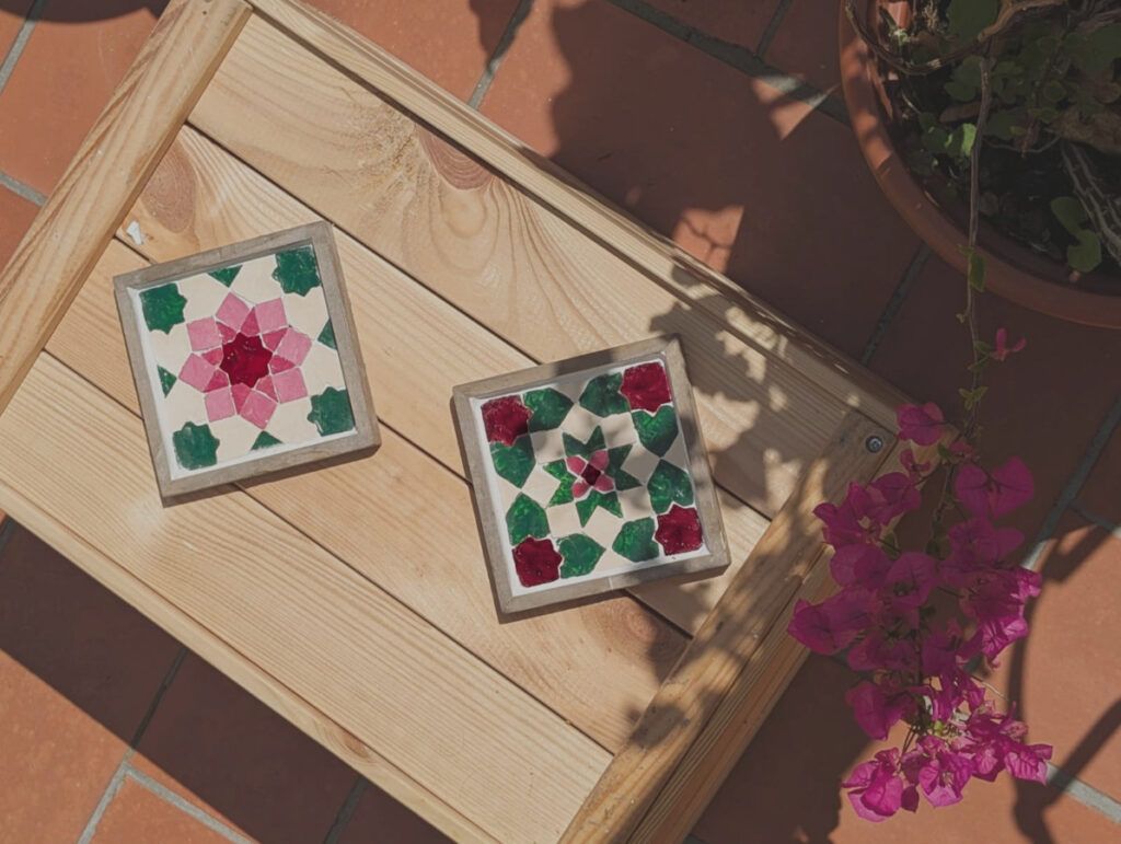 Two Florals coasters on a wooden table outdoors with bougainvillea